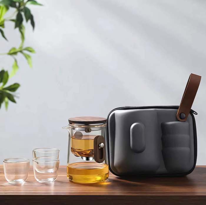 Théière Kaji portable en verre transparent avec infuseur, tasses assorties et pochette de transport élégante.